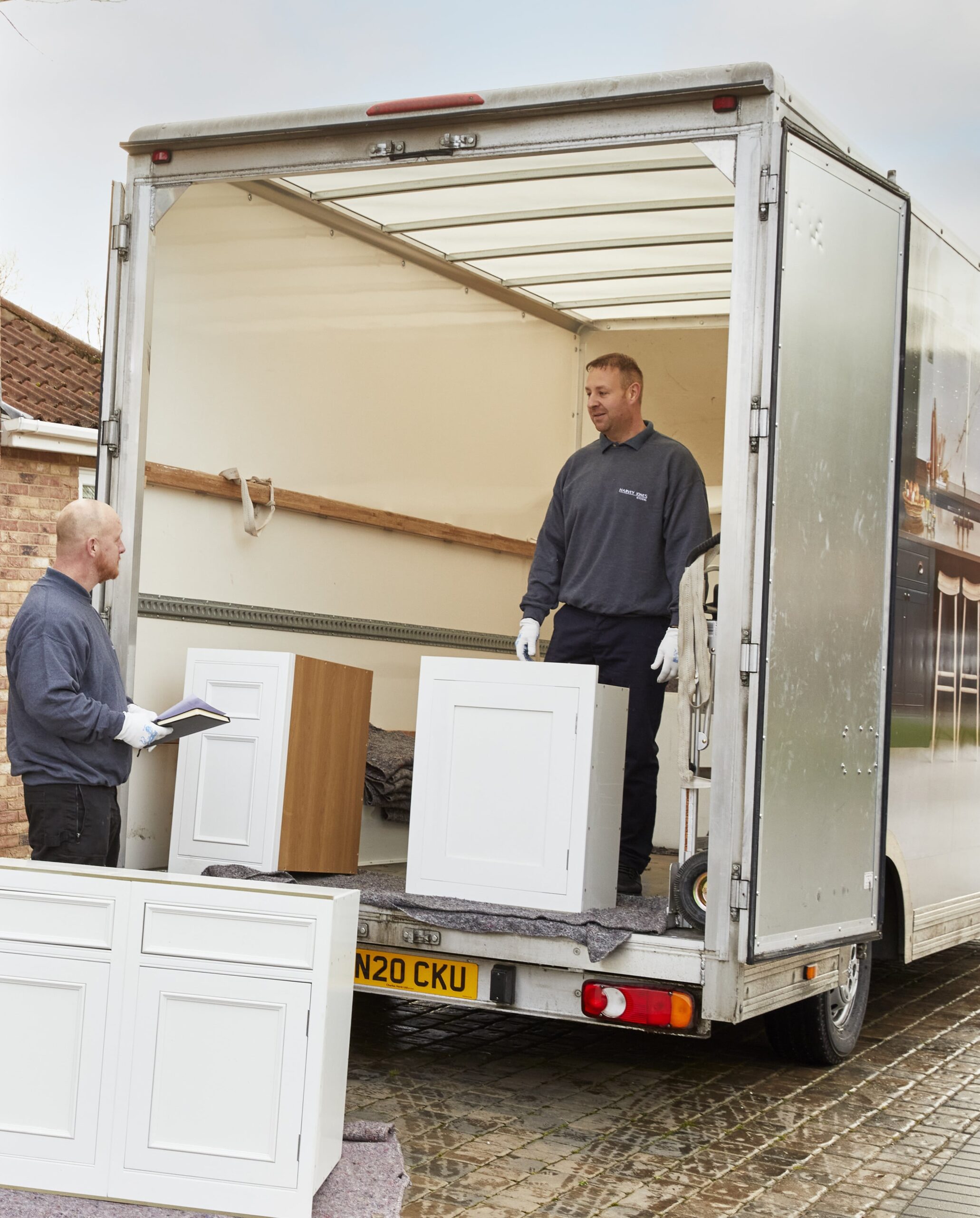 Delivery of Harvey Jones kitchen cabinetry shown by two men unloading cabinetry off a van