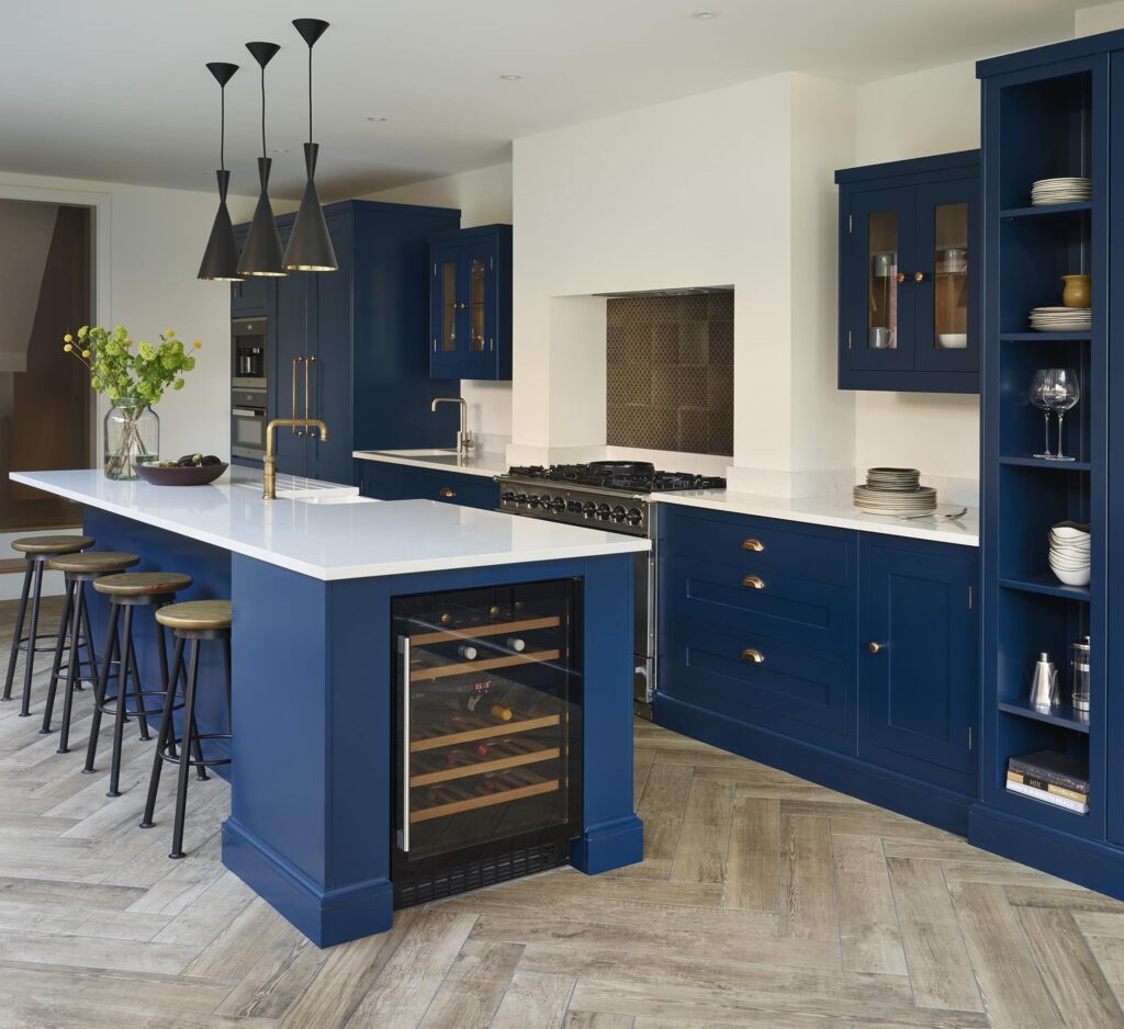 Rich blue kitchen island with white worktop with integrated sink with brass tap and wine fridge end panel