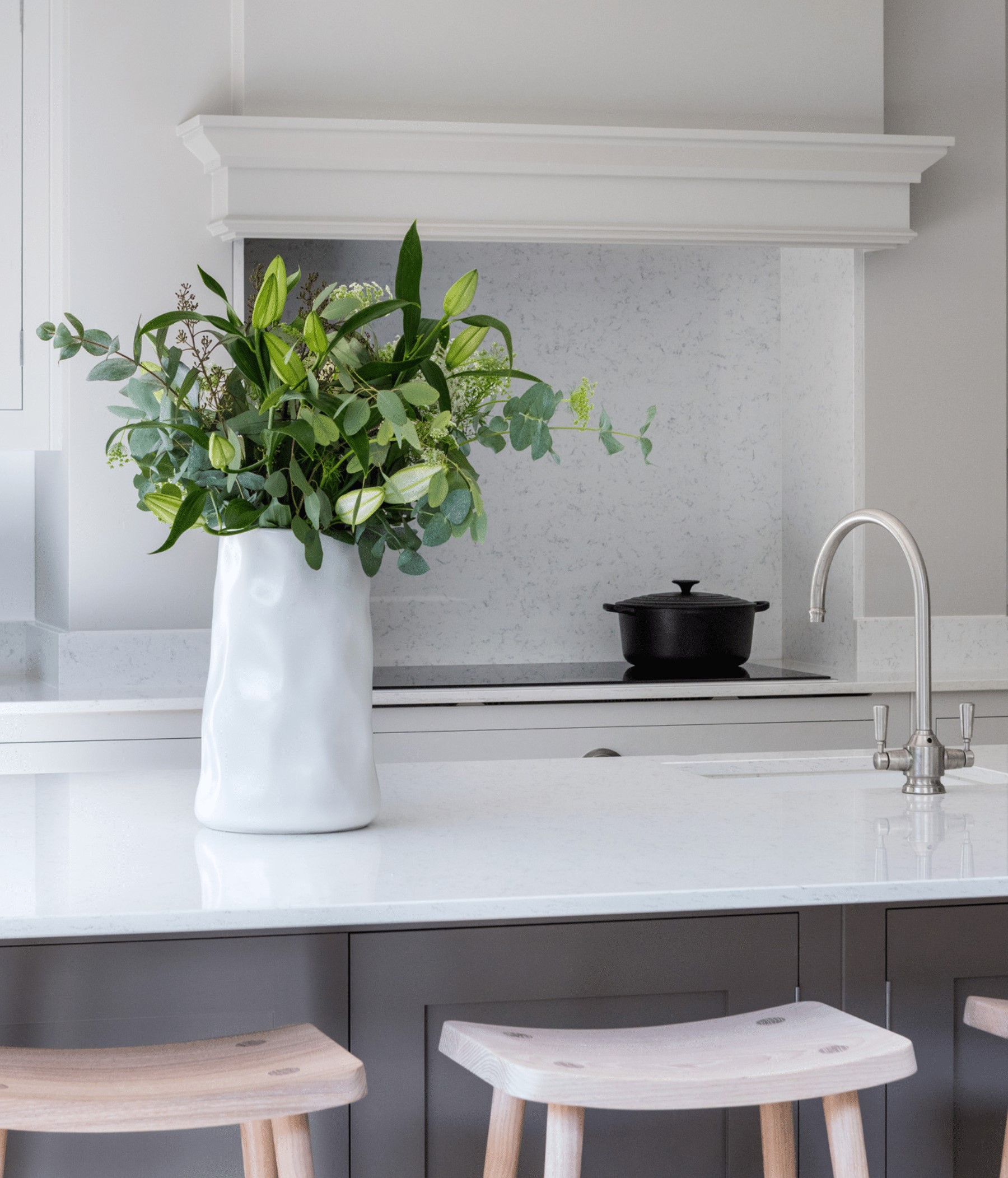 Kitchen installation of a white kitchen design featuring a white kitchen island and wooden smile stools