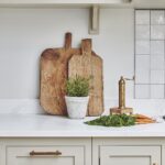 Beige Arbor kitchen cabinetry with a white worktop featuring wooden chopping boards