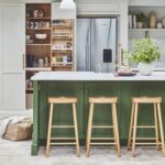 Kitchen larder and American style refrigerator with a green kitchen island featuring a white worktop