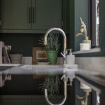 Teal Arbor kitchen cabinetry alongside a white sink and silver tap