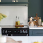 Teal Arbor kitchen cabinetry with a white splashback against the cooking area