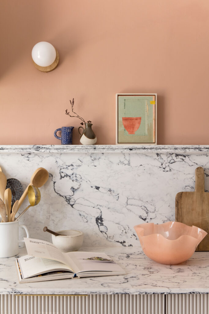 White and grey marble splashback with open shelving against peach wall