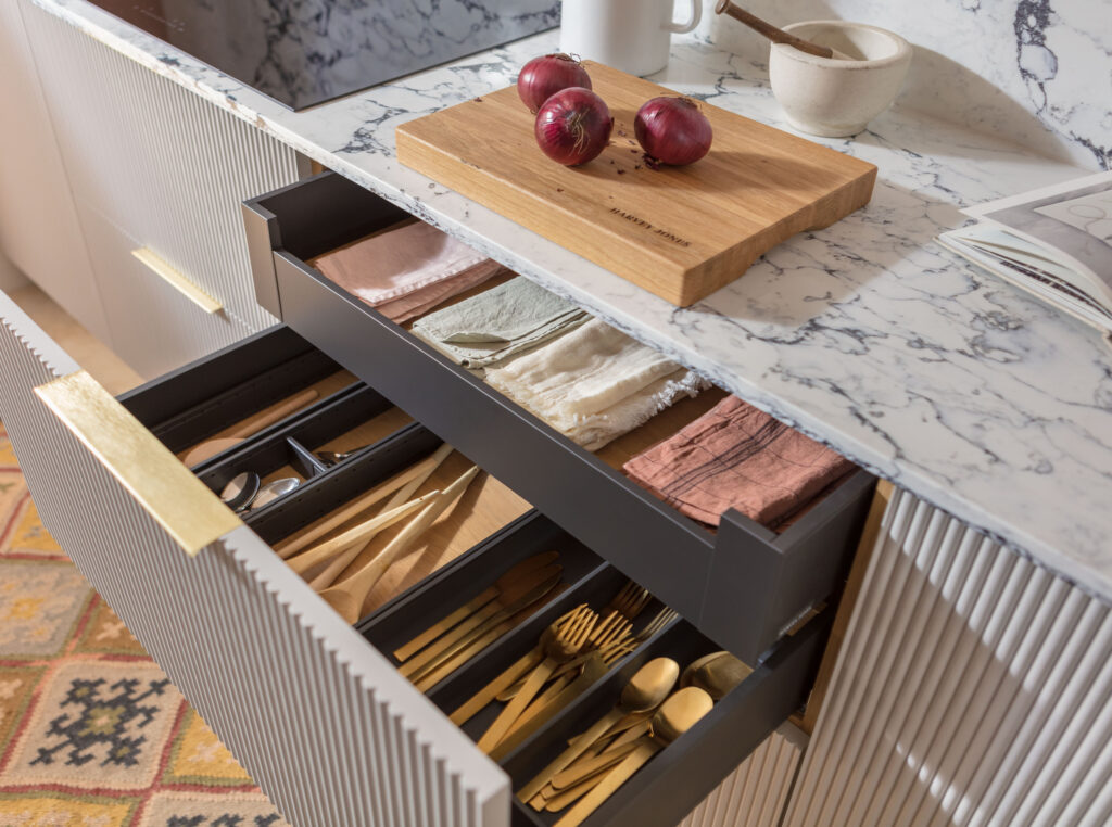 Reeded kitchen drawer open to show black interior and organised storage