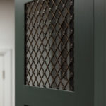 Closeup of green Shaker kitchen cabinet door with crosshatch window