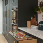 Green Shaker kitchen drawer open to show organised storage