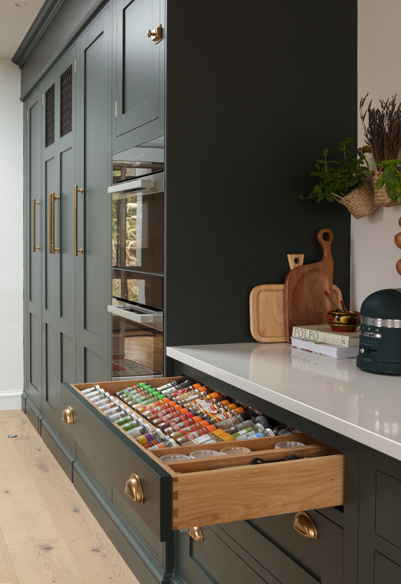 Green Shaker kitchen drawer open to show organised storage
