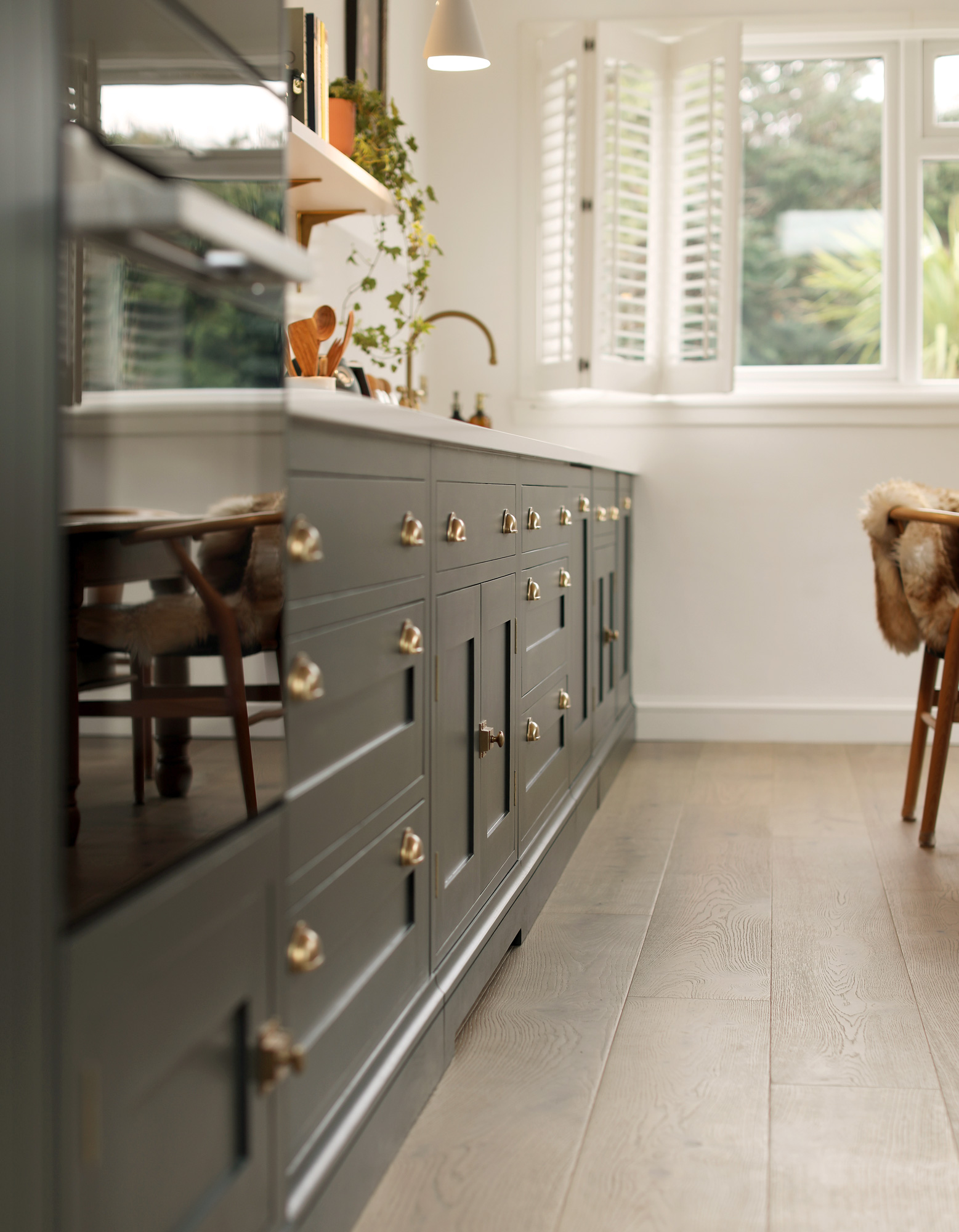 Green Shaker kitchen cabinetry with burnished brass handles