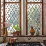 Kitchen cooker area featuring a monochrome marble splashback against large rectory arched windows