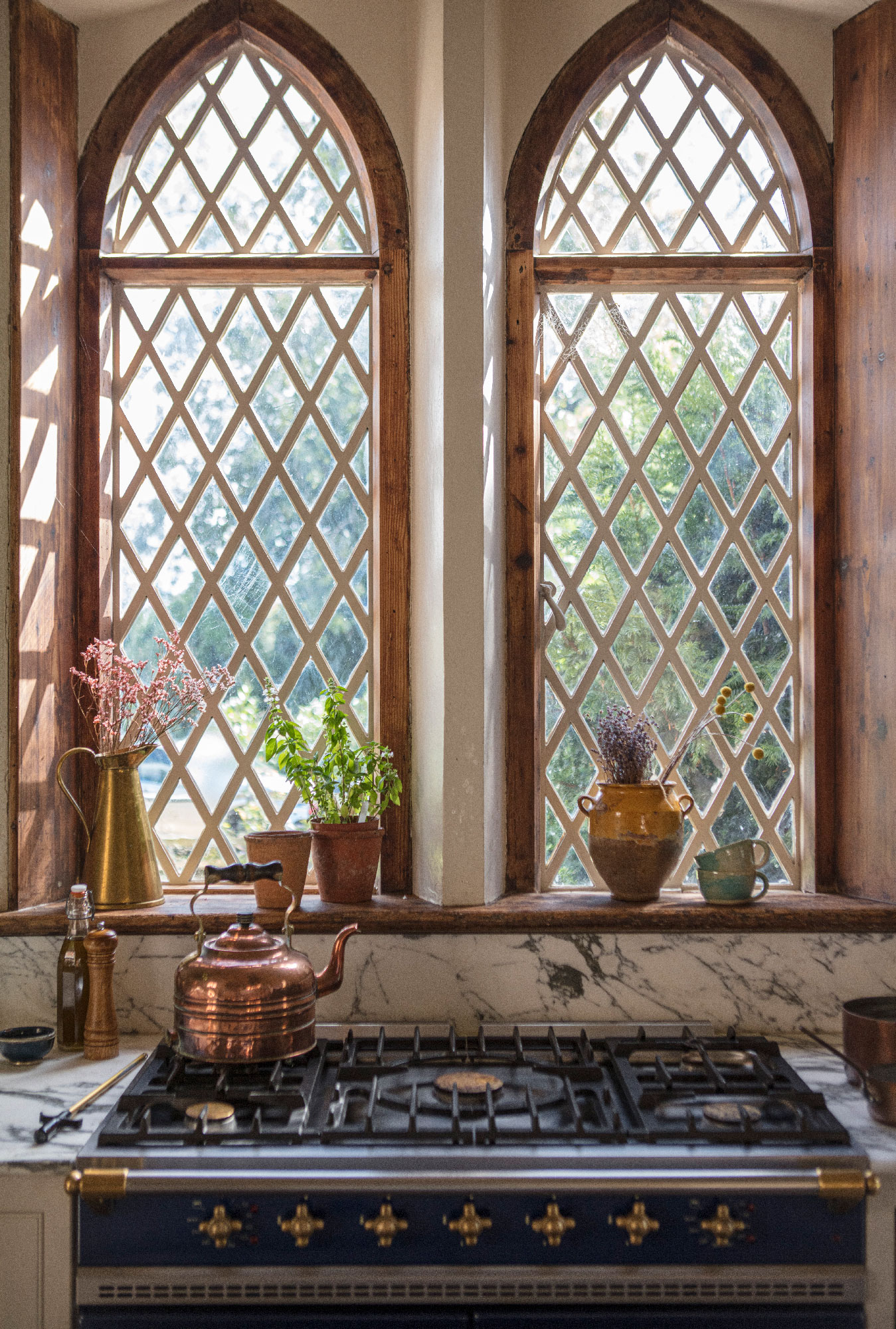 Kitchen cooker area featuring a monochrome marble splashback against large rectory arched windows