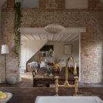 Dark wooden kitchen island featuring a white basin sink and gold tap