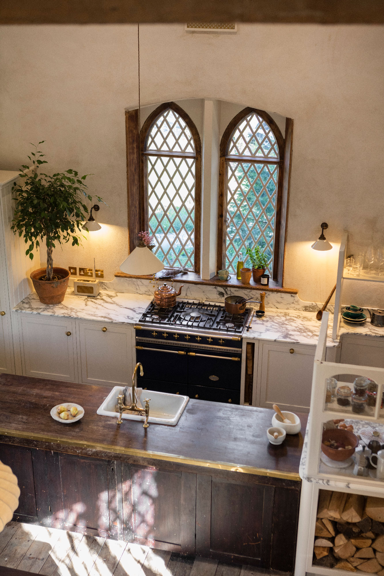 Overlooking view of an Arbor kitchen design in a renovated rectory, featuring cream cabinetry and dark wooden kitchen island