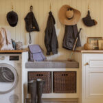 Cream and white boot room featuring grey bench seating, brown storage baskets and coat hooks above