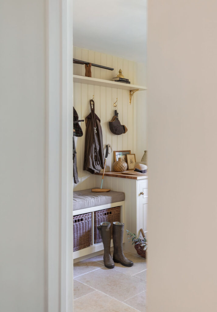 Cream and white boot room with bespoke furniture, hanging space for coats and wall panelling