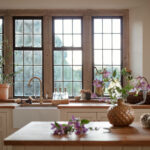 White Original kitchen cabinetry with white sink and brass tap against wooden framed windows
