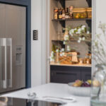 Walk-in pantry open to show organised shelving and workspace