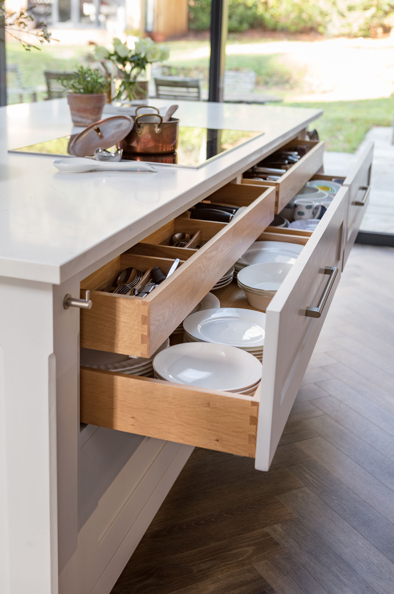 White Shaker kitchen island with open drawers revealing oak interior and organised crockery
