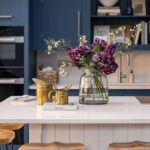 White Shaker kitchen island with white worktop and wooden bar stools