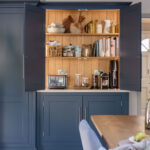 Blue Shaker kitchen unit open to reveal hidden workspace and organised shelving