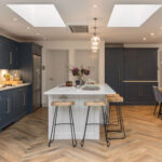 Blue Shaker kitchen cabinetry and white kitchen island with white worktops overlooking open plan dining area