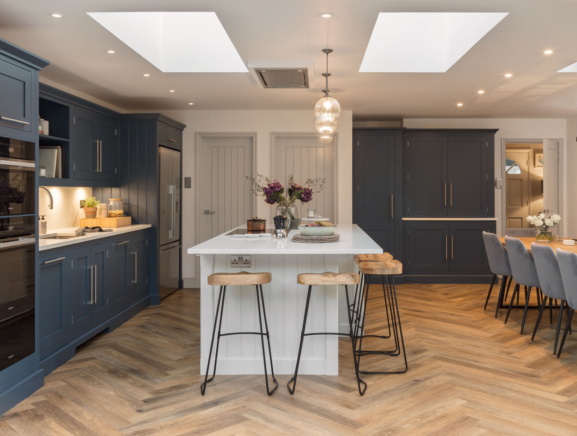 Blue Shaker kitchen cabinetry and white kitchen island with white worktops overlooking open plan dining area