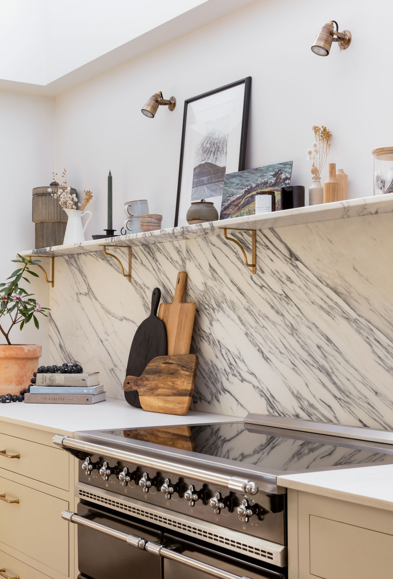 Marble splashback against white kitchen works tops and beige cabinetry containing a cooker