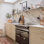 Beige Arbor kitchen cabinetry featuring a marble splashback against the cooker