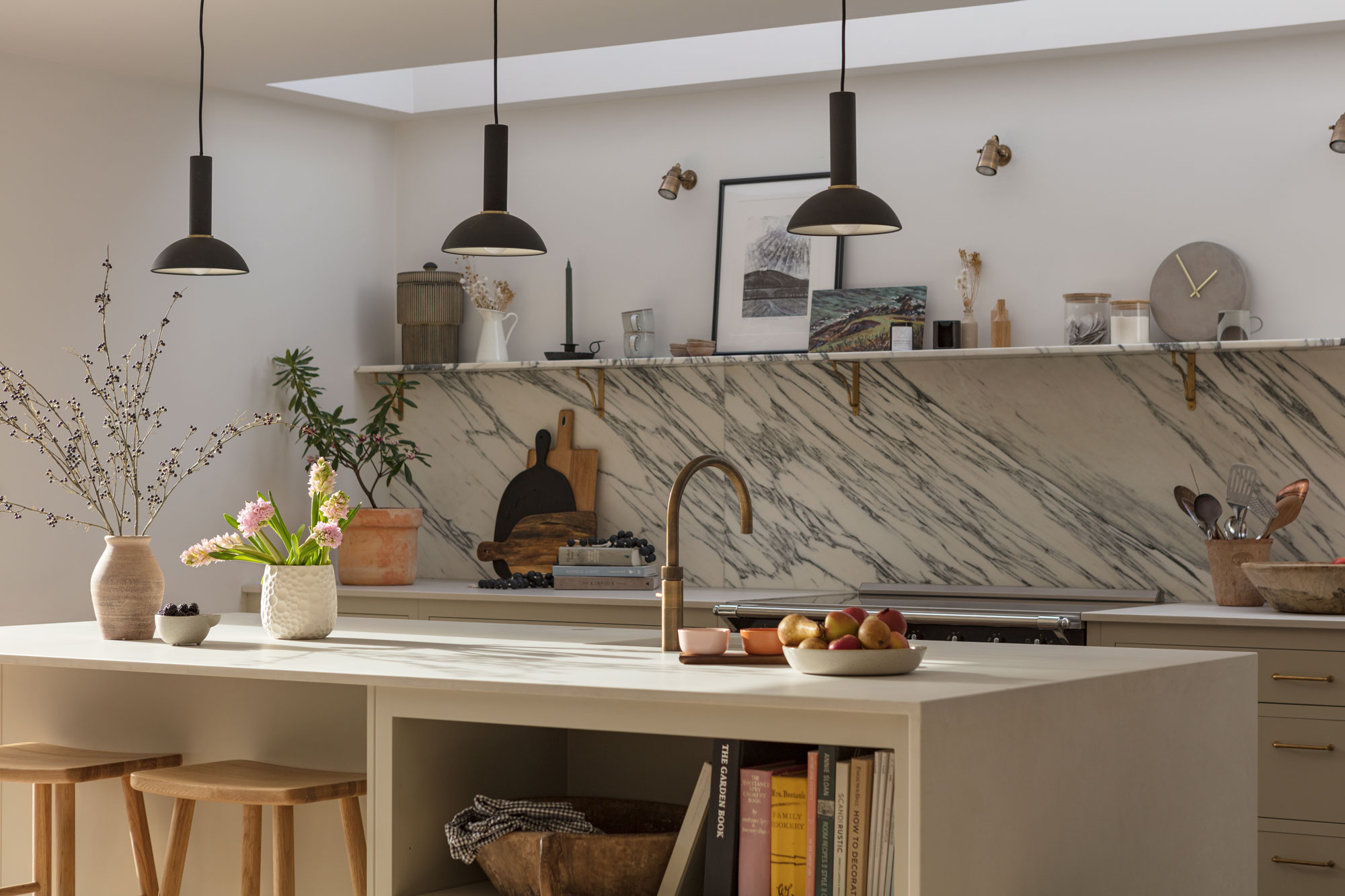 Beige kitchen island with white worktop in front of a black and white marble splashback