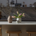 Wooden stools around a beige kitchen island with a white worktop