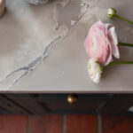 White marble worktop with teal kitchen cabinetry