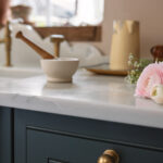 Closeup of teal Original kitchen cabinet with brass handle and white marble worktop