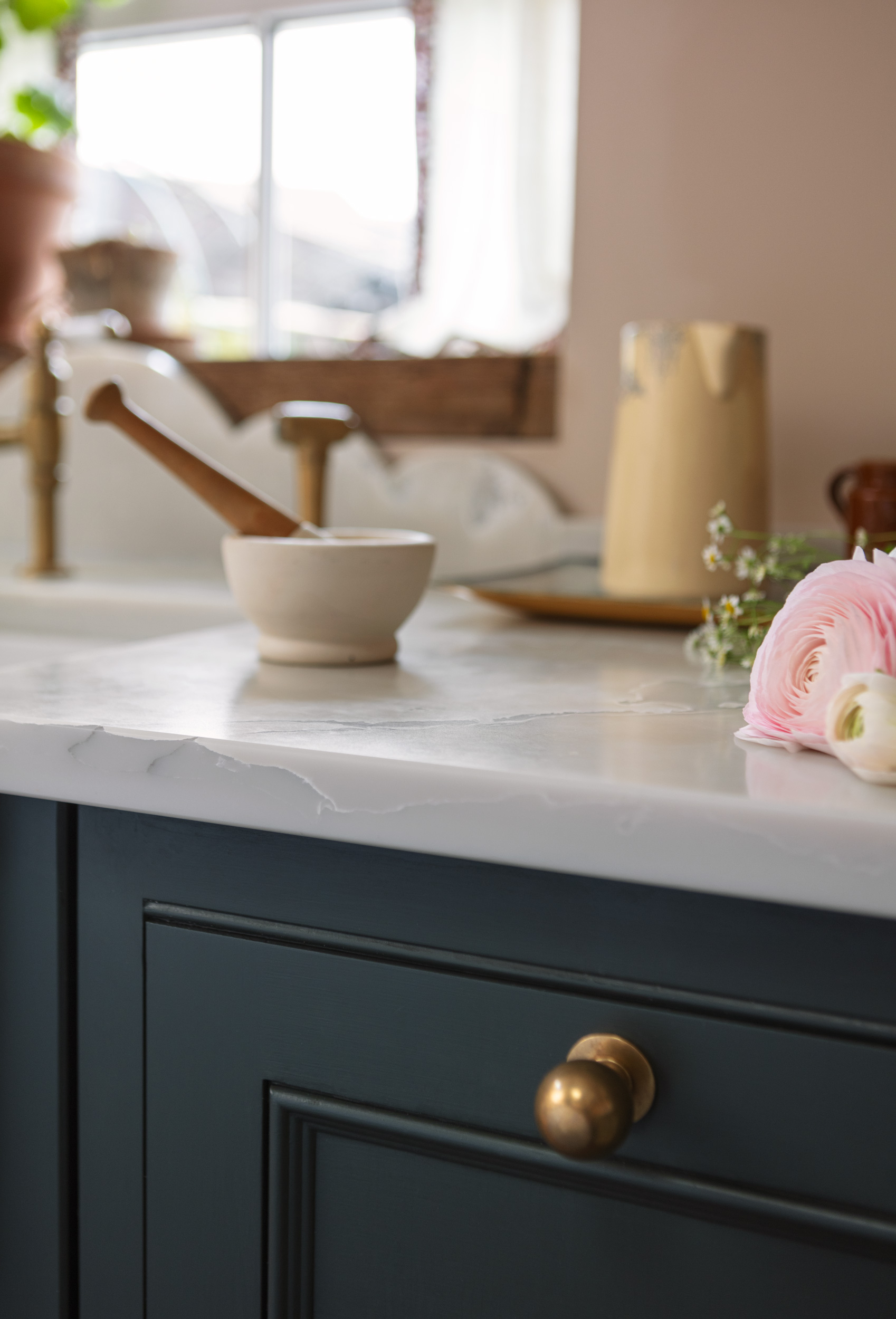 Closeup of teal Original kitchen cabinet with brass handle and white marble worktop