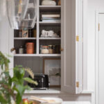 Large white Shaker kitchen unit open to show hidden workspace and organised shelving