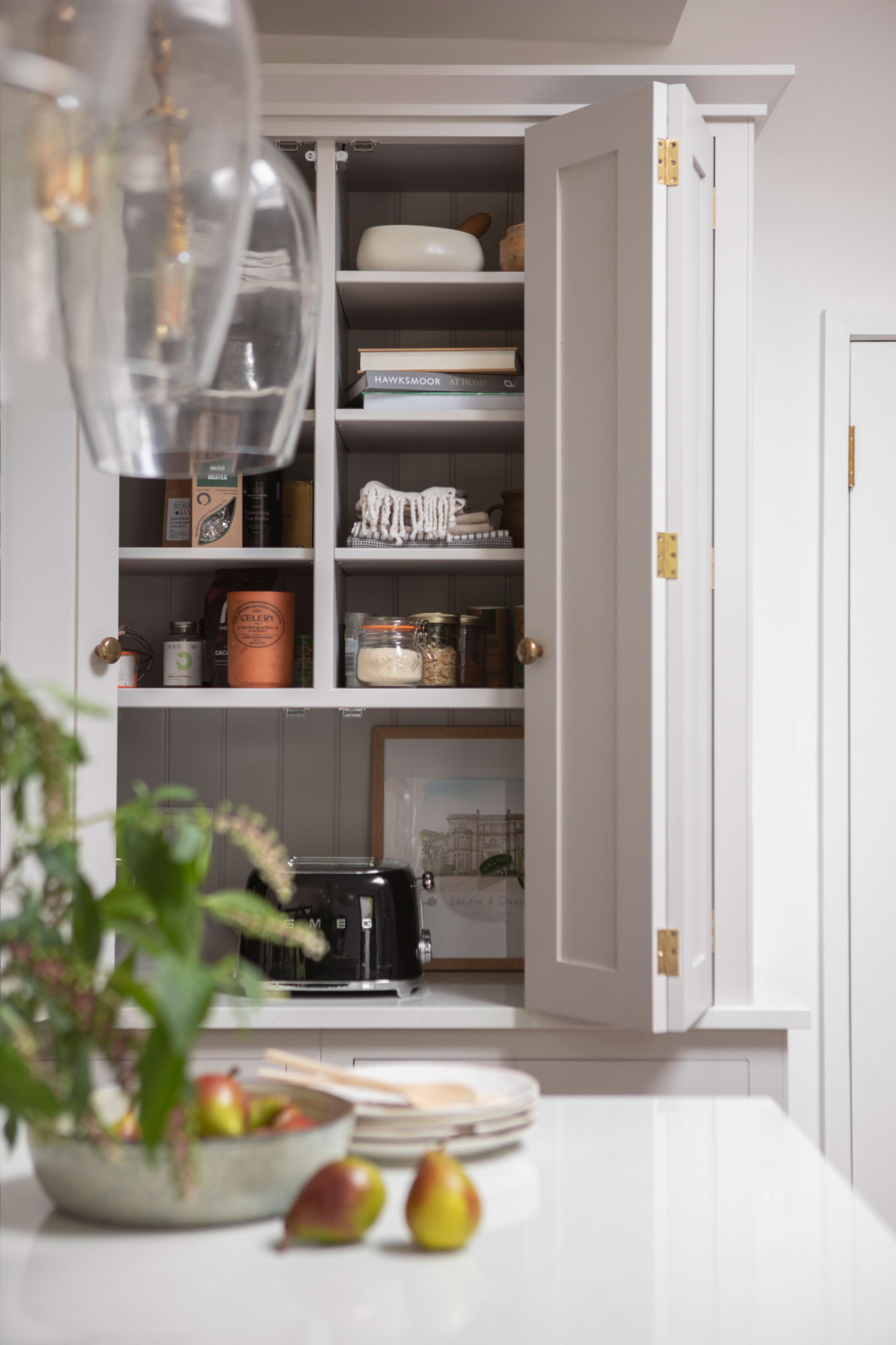 Large white Shaker kitchen unit open to show hidden workspace and organised shelving