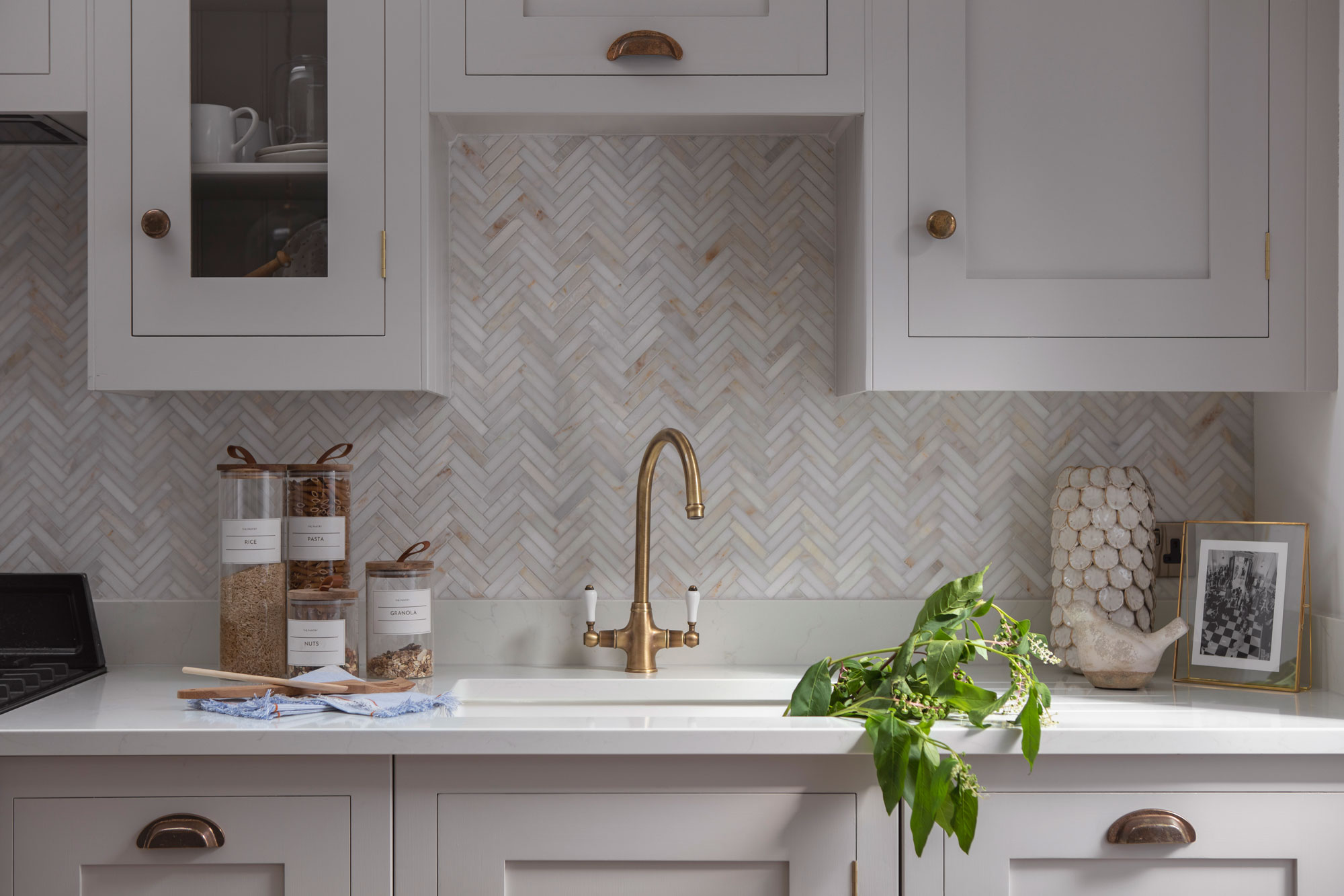 White Shaker kitchen cabinetry with white worktop and beige herringbone tiled splashback