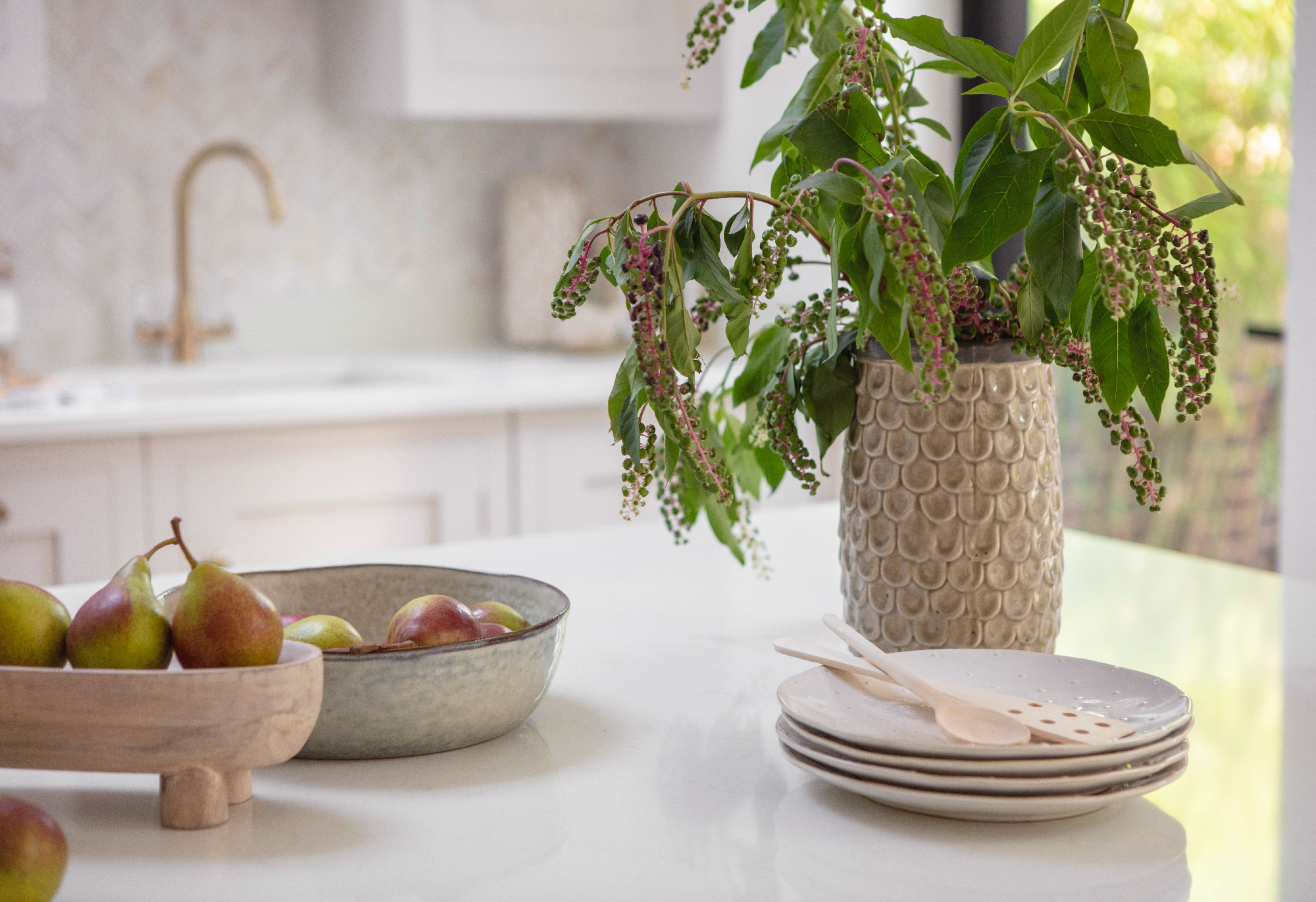 White kitchen island worktop with potted plant and stacked crockery
