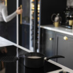 Closeup of integrated oven within a white kitchen island featuring a white marble worktop