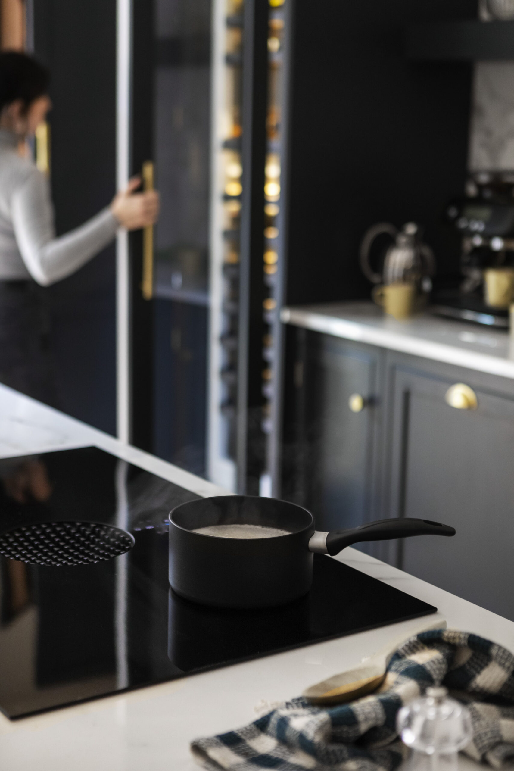 Closeup of integrated oven within a white kitchen island featuring a white marble worktop
