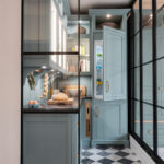 Elegant walk-in pantry design with checkered flooring, pale blue cabinetry, and integrated fridge, blending classic styling with modern kitchen luxury.