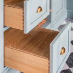 Luxury pantry drawers including dovetail joint detail labeled for bread and biscuits with oak interiors and brass handles.