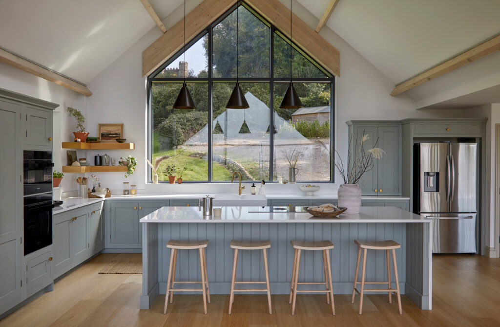 Light blue kitchen with natural light in gable end window with natural materials and curated bespoke design features
