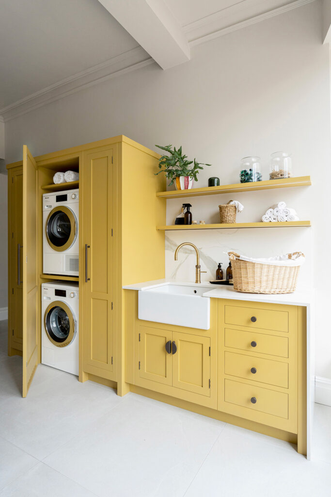 Tall yellow storage unit in a luxury utility room with hidden shelving for cleaning and laundry products.
