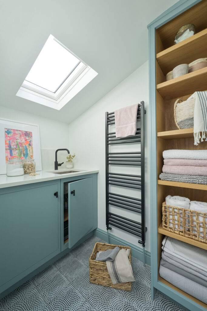 Blue utility room with sink, tall storage, towel rail and bespoke cabinetry