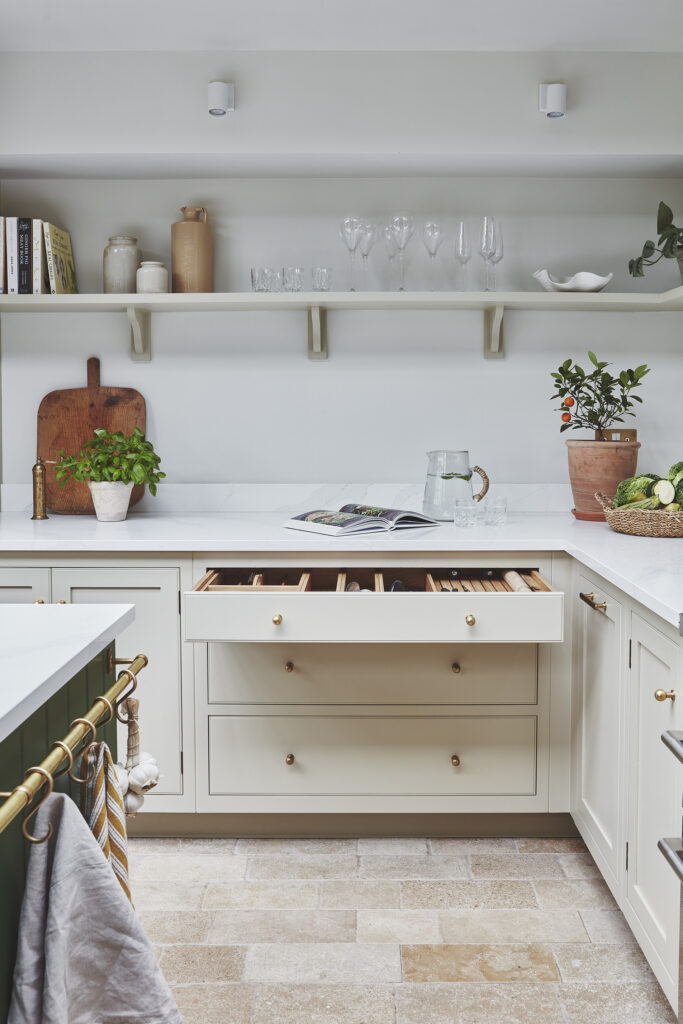 Neutral minimal kitchen design with open shelving displaying glassware and ceramics and oak drawer internals