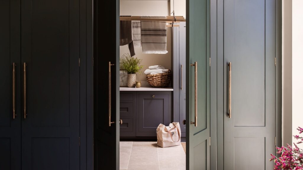 Green Harvey Jones kitchen doors open to show hidden utility room