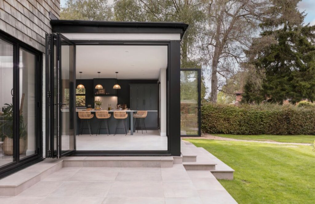 Teal kitchen design seen from large open black framed glass sliding doors