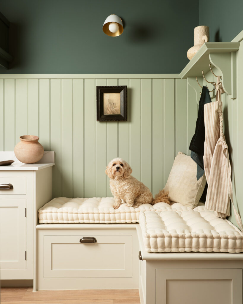 Green and cream bespoke boot room with bench seating, wall panelling and drawer storage