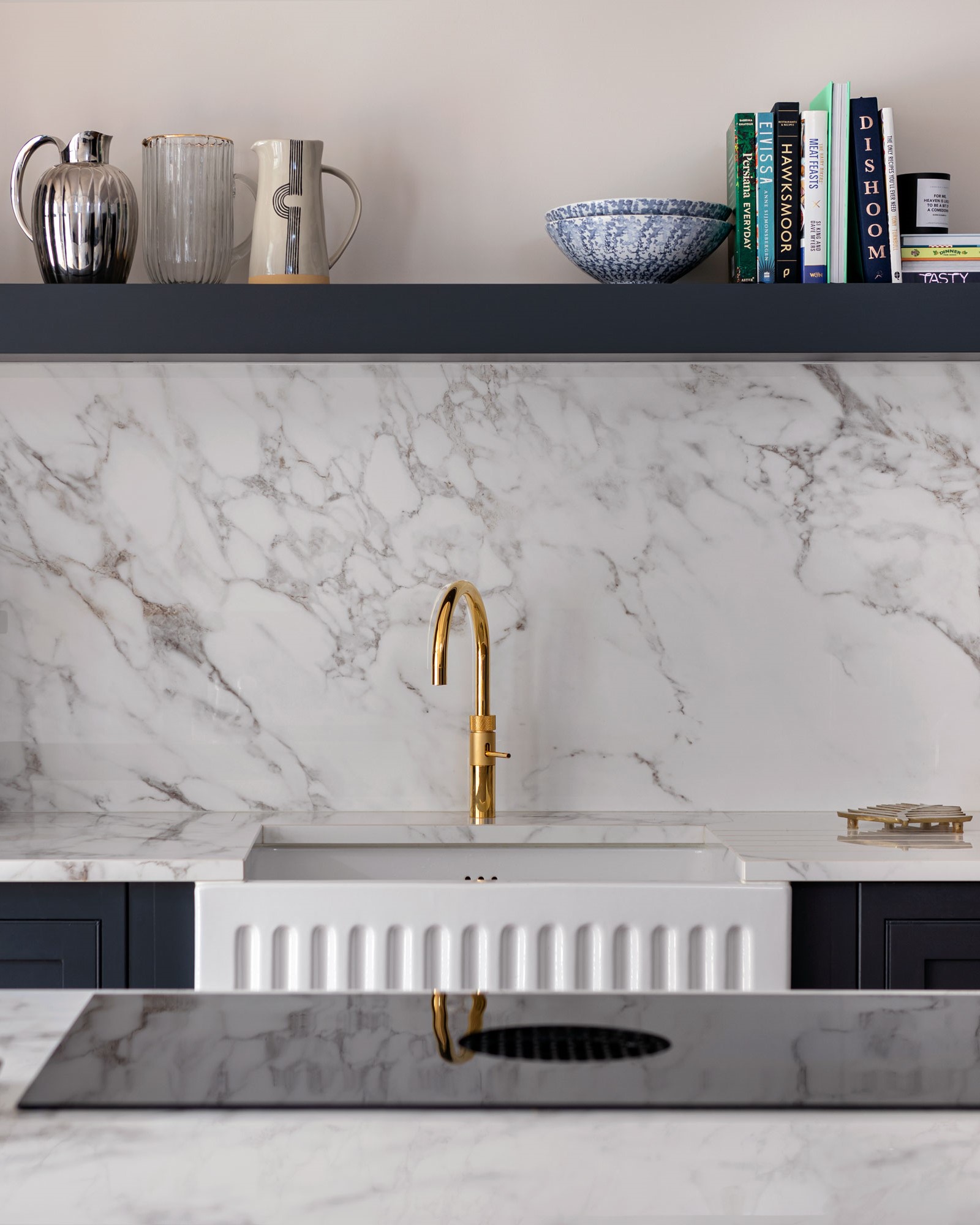 White basin sink with brass tap against a white marble splashback