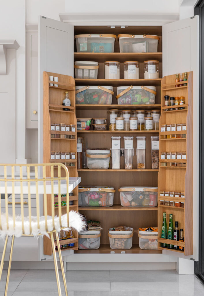 White kitchen pantry larder with oak interior open to show organised storage
